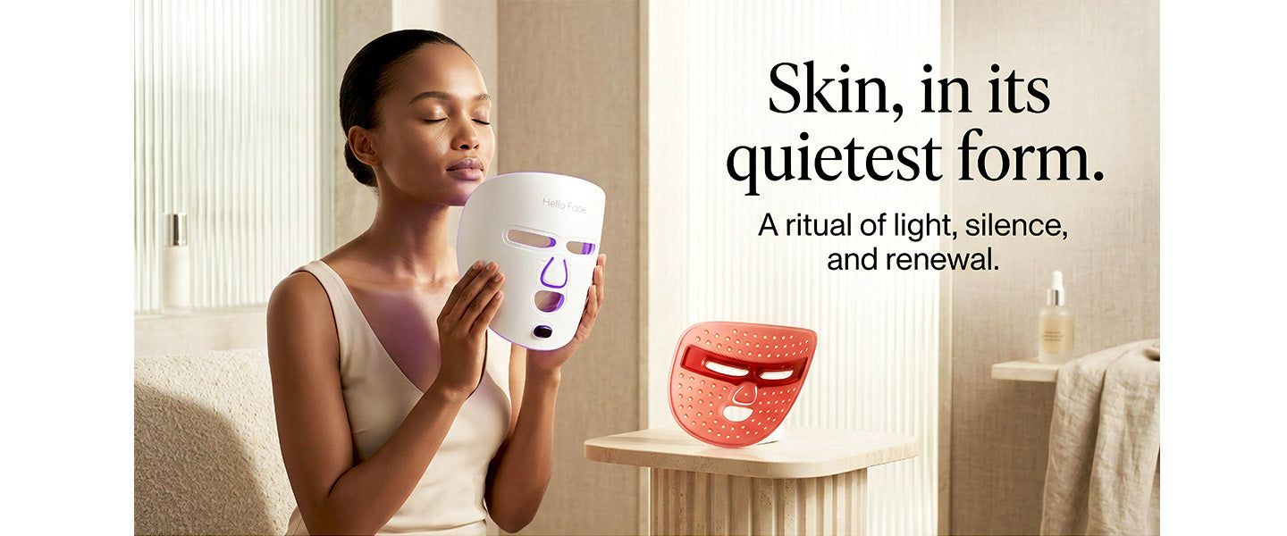 Woman holding a white device with a red mask next to it, in a softly lit room.